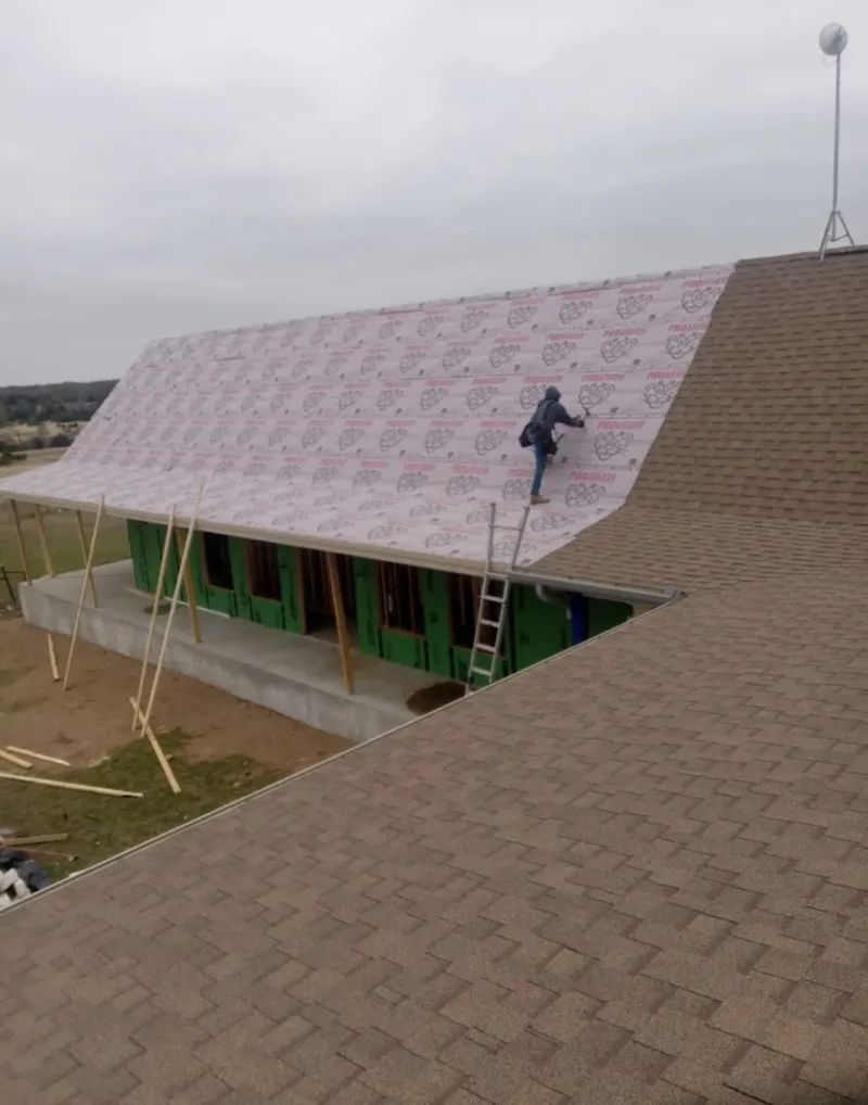 Worker preparing underlayment for a metal roof installation in Pontiac
